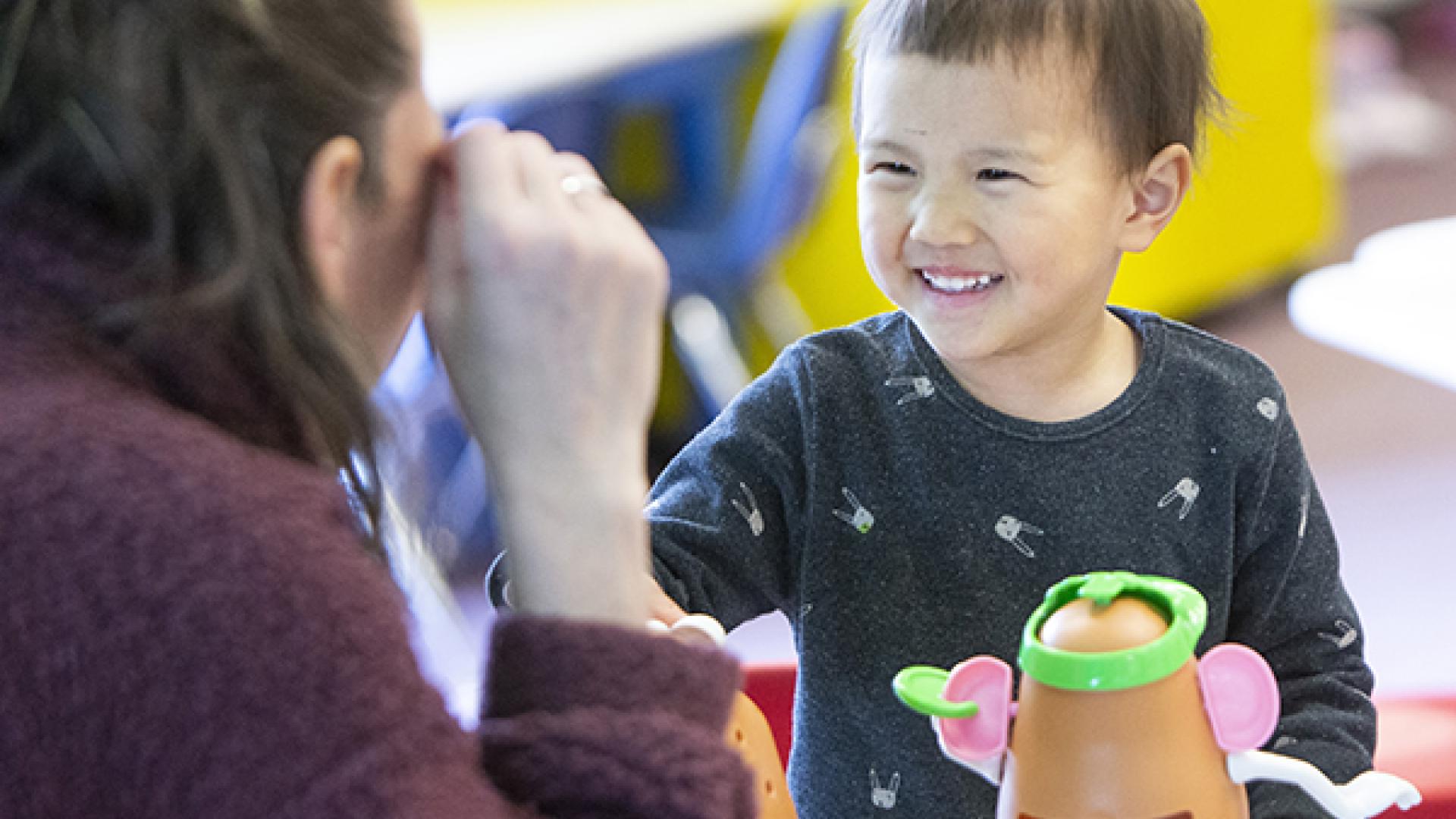 A child playing with Mr. Potato Head and instructor