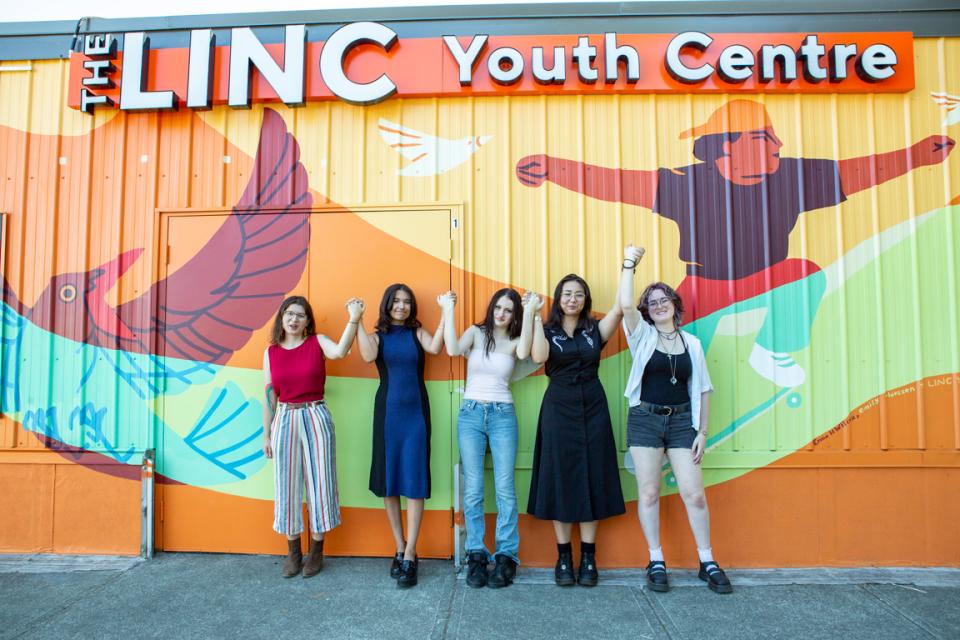 Local illustrator and muralist Emily Thiessen stands with four local youth artists in front of the new mural they created at The LINC Youth Centre