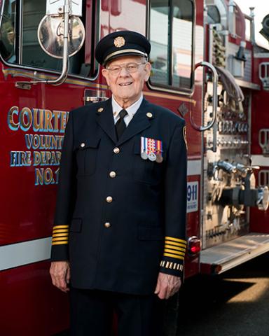 Lawrence Burns standing by a fire truck in uniform
